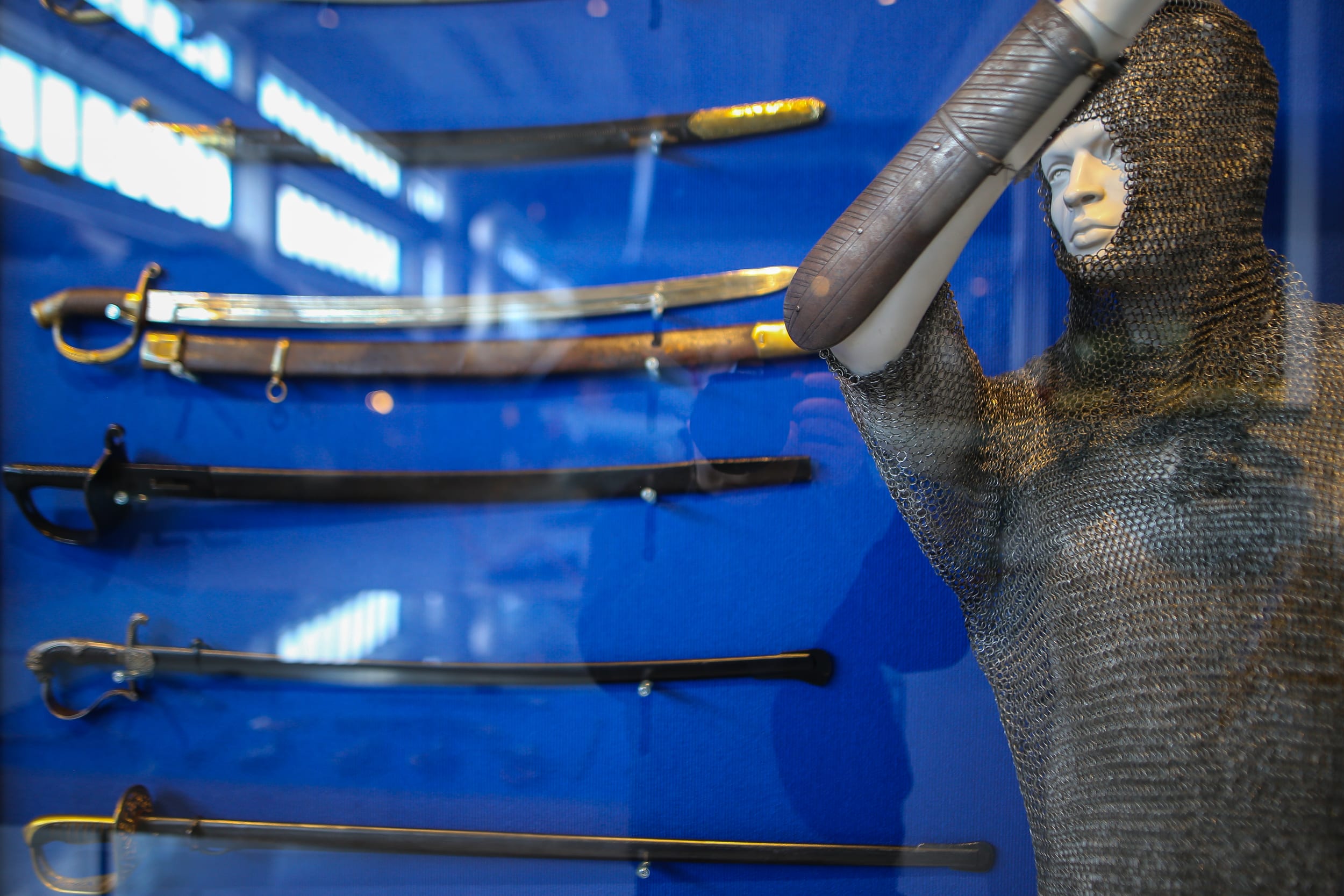 Arne Somersalon asekokoelma, vitriinissä sapeleita ja mallinukke, jolla rengaspaita ja -huppu.