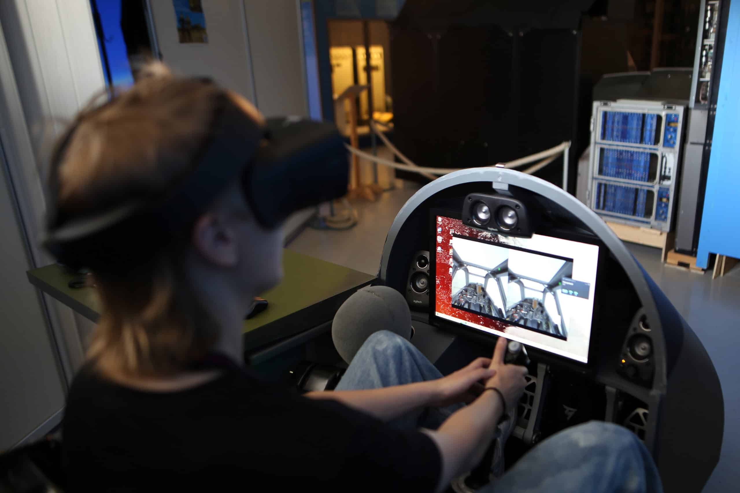 Asiakas istuu simulaattorin ohjaamossa vr-kypärä päässään ja pitää käsillään kiinni ohjaussauvasta.